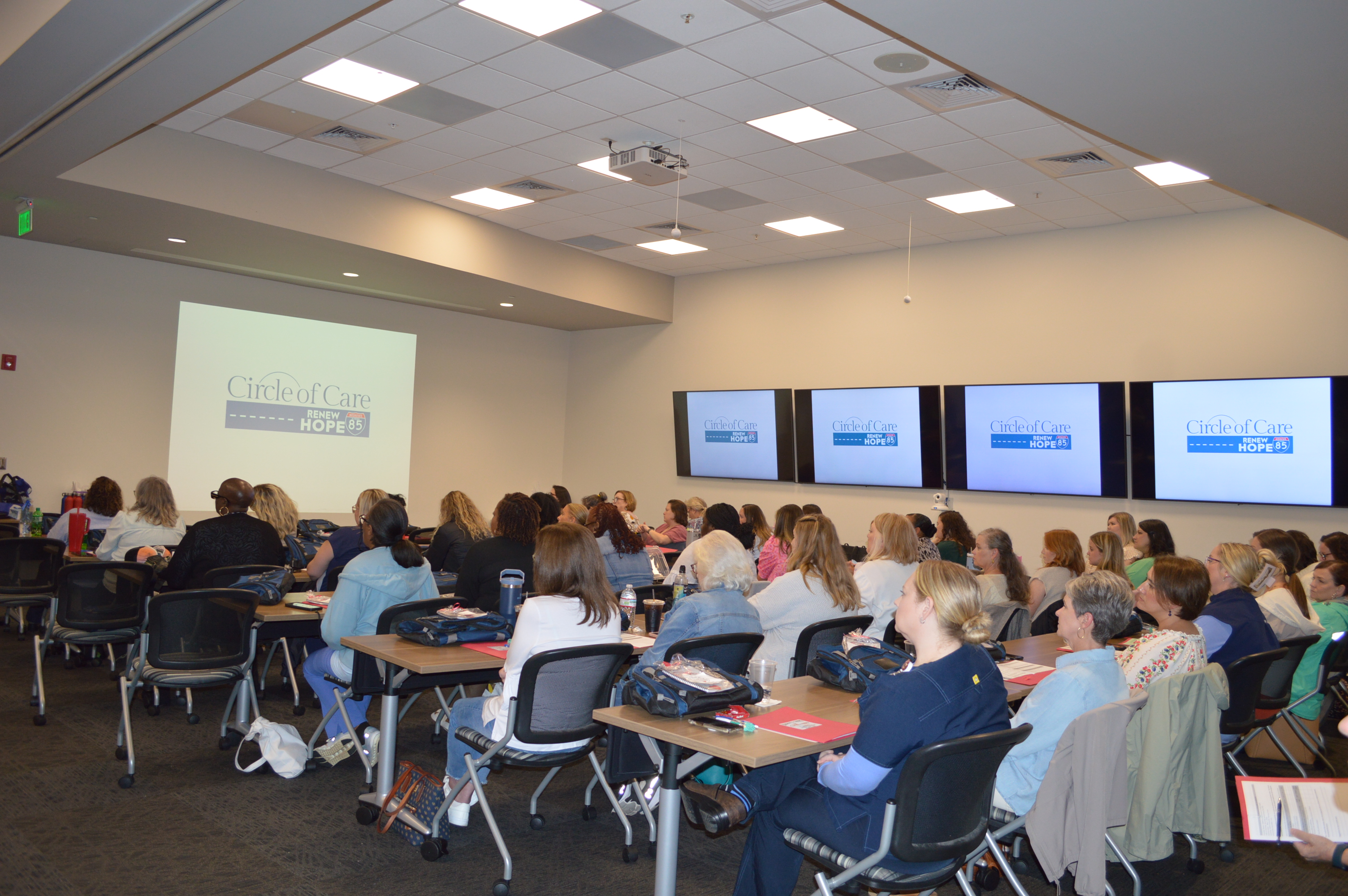 Attendees of a conference looking at screens that say Circle of Care.
