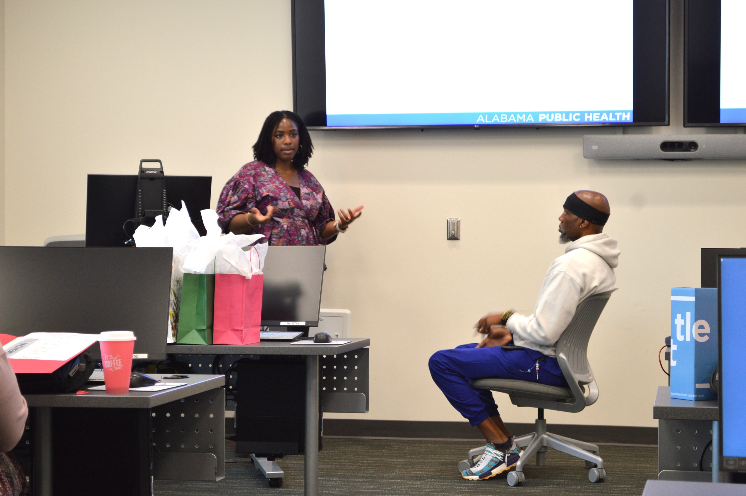A man and woman play out a health care scenario in front of a group of attendees.
